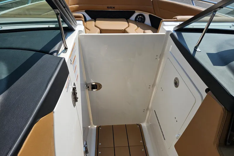 Slide: The Image of 2025 Chaparral 267 SSX boat interior with tan and black seating, open storage compartment. - 30