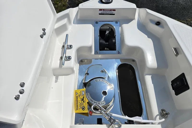 Slide: The Image of 2025 Chaparral 267 SSX boat anchor compartment with chrome fittings and safety warning label. - 32