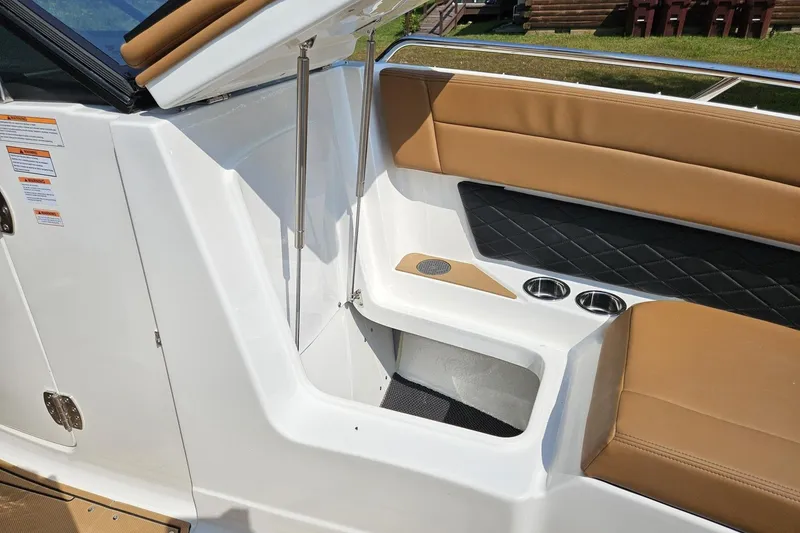 Slide: The Image of 2025 Chaparral 267 SSX boat interior with tan seating and storage compartment. - 40