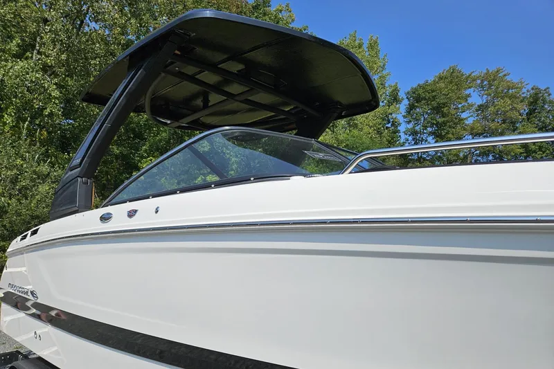 Slide: The Image of 2025 Chaparral 267 SSX boat with sleek design and black canopy against blue sky. - 5