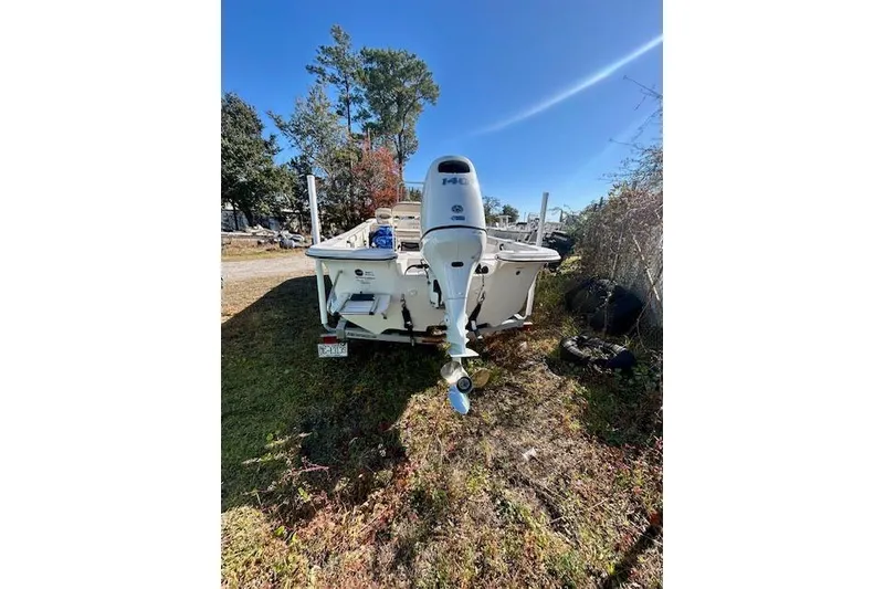 Slide: The Image of 2023 Carolina Skiff 21 LS boat with outboard motor, parked on grass under clear blue sky. - 8