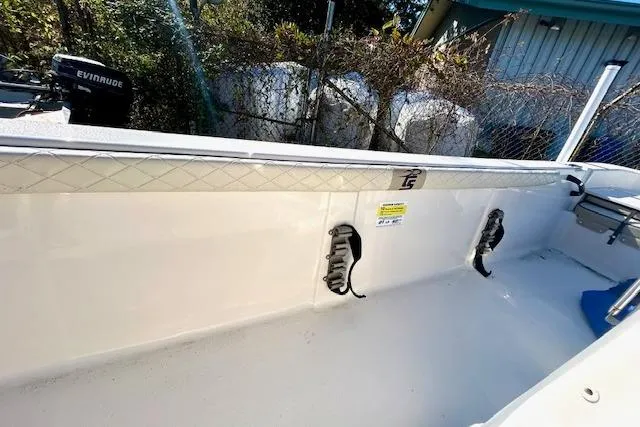 Slide: The Image of 2023 Carolina Skiff 21 LS boat interior with Evinrude motor, white deck, and storage compartments. - 9