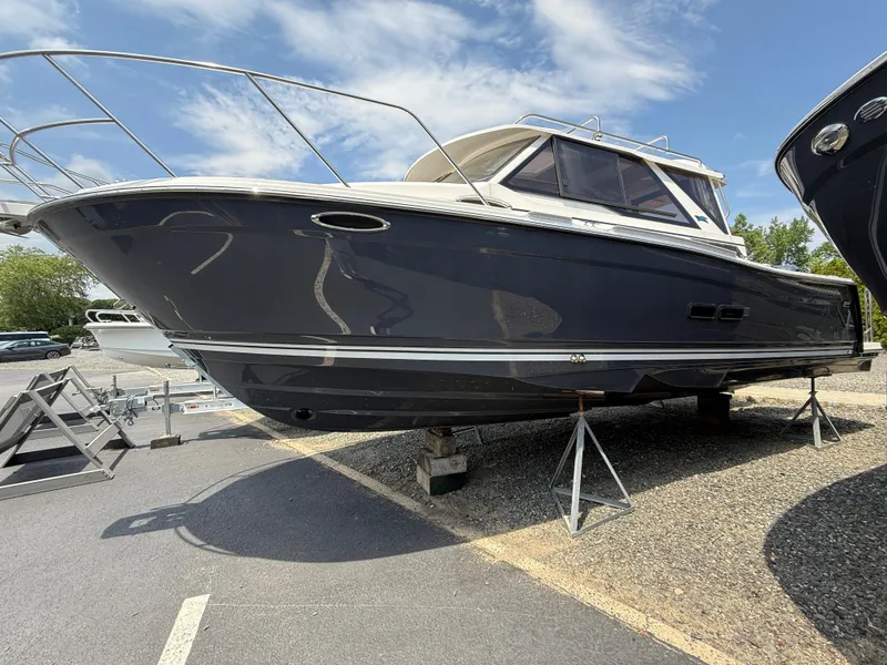 The Image of 2025 Cutwater C-288 Coupe LE boat on stands, under a clear blue sky. - 0
