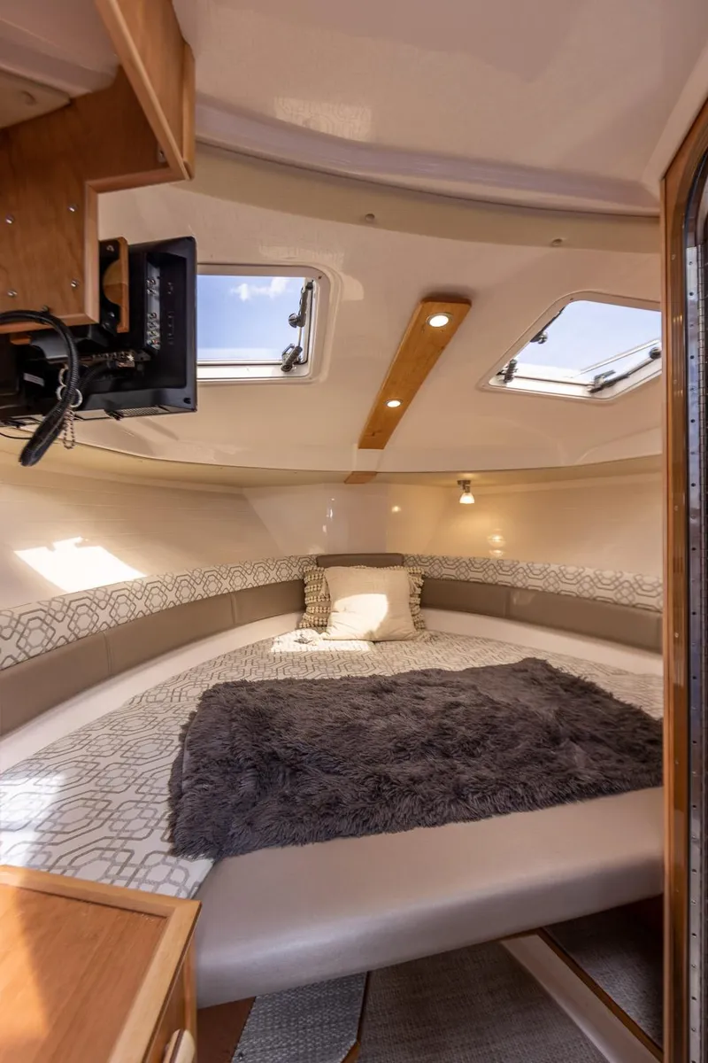 Slide: The Image of Interior of 2025 Cutwater C-288 Coupe LE, featuring cozy cabin with skylights and plush bedding. - 26