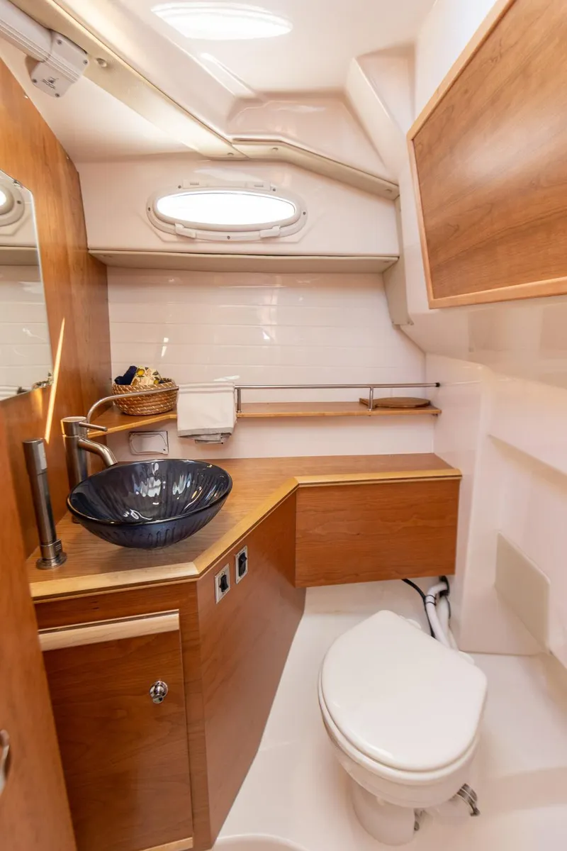 Slide: The Image of 2025 Cutwater C-288 Coupe LE bathroom with modern sink and wooden cabinetry. - 29