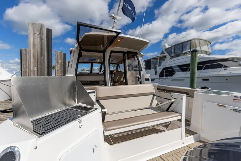 Slide: The Image of 2025 Cutwater C-288 Coupe LE boat with outdoor seating and grill, docked under blue sky. - 7