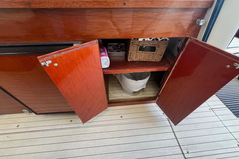 Slide: The Image of Open wooden cabinet on 1984 Skiff Craft 26 Runabout boat, revealing storage items. - 13