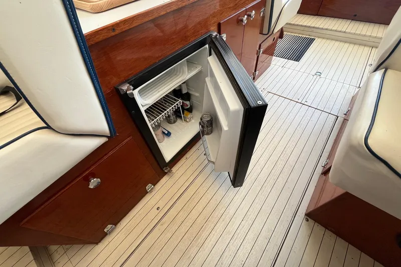 Slide: The Image of Open mini fridge inside 1984 Skiff Craft 26 Runabout boat, showing beverages and wooden interior. - 16