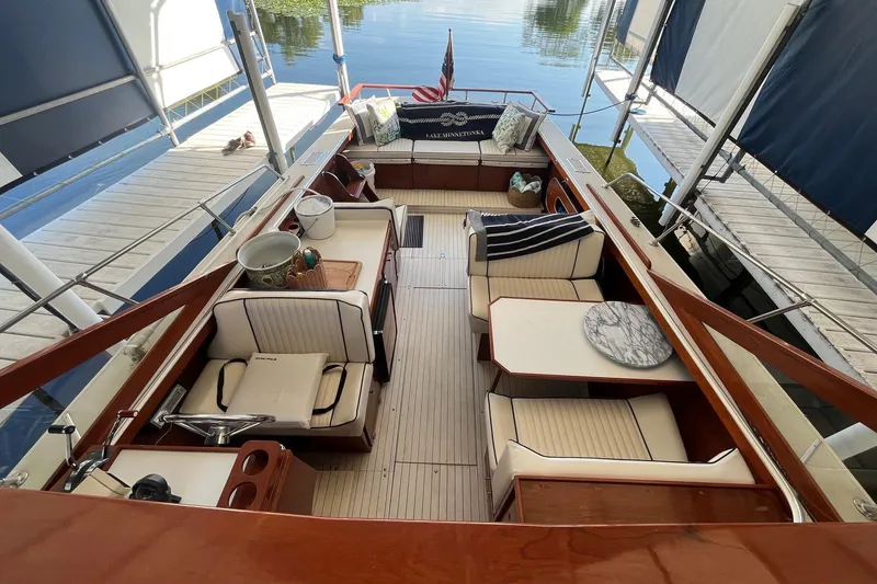 Slide: The Image of 1984 Skiff Craft 26 Runabout with elegant seating and wooden interior docked by the water. - 25