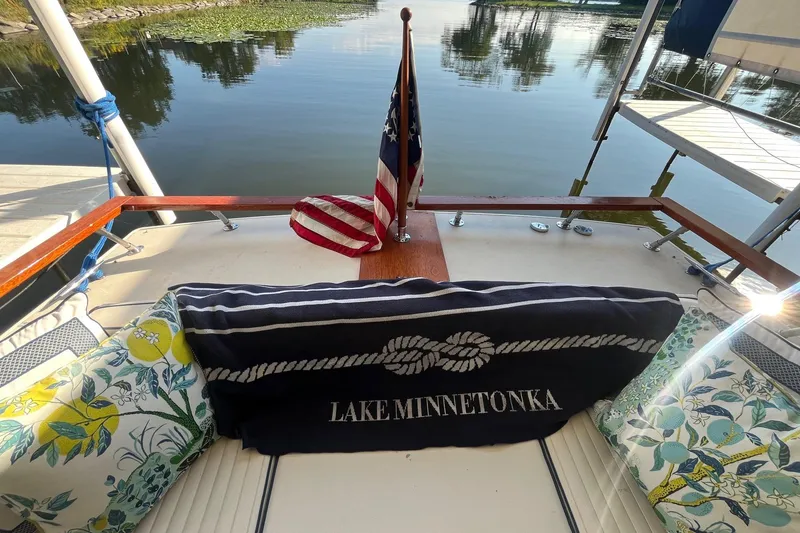 Slide: The Image of 1984 Skiff Craft 26 Runabout on Lake Minnetonka, featuring decorative cushions and American flag. - 27