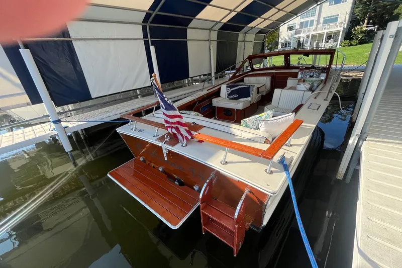 Slide: The Image of 1984 Skiff Craft 26 Runabout docked under a canopy, featuring classic wooden design. - 4