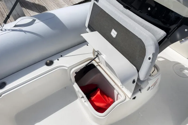 Slide: The Image of 2023 Zodiac N-ZO 680 boat storage compartment with open lid, revealing red item inside. - 17