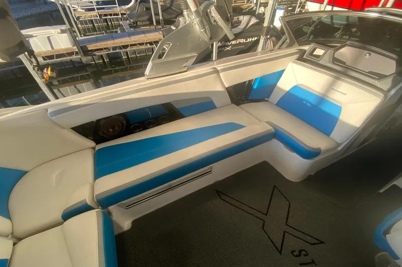 Slide: The Image of 2019 MasterCraft XStar interior with blue and white seating, docked at marina. - 11