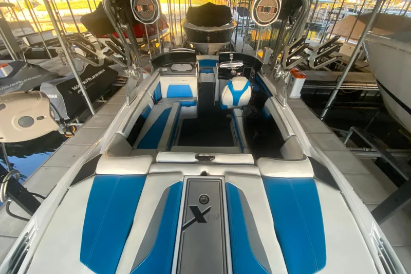 Slide: The Image of 2019 MasterCraft XStar boat interior with blue and white seating, docked in a marina. - 32
