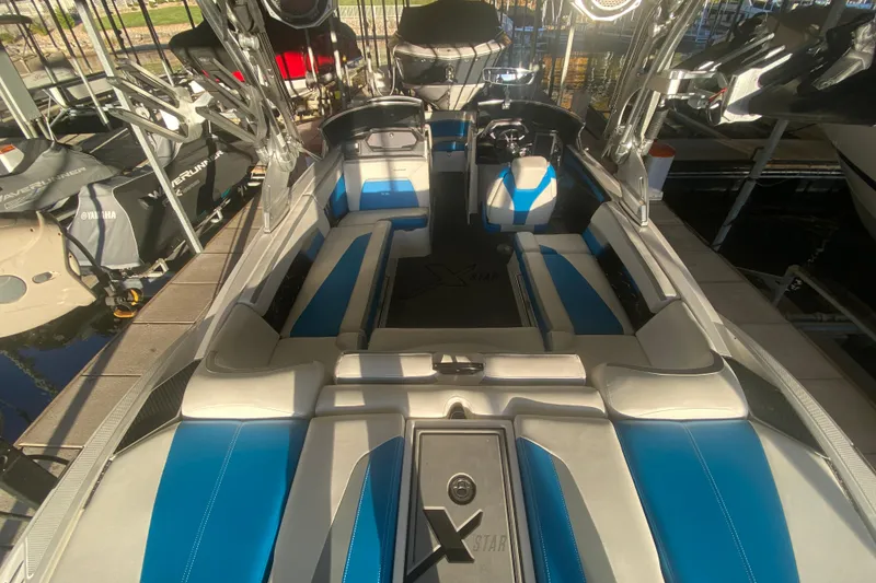 Slide: The Image of 2019 MasterCraft XStar boat interior with blue and white seating, docked in marina. - 8
