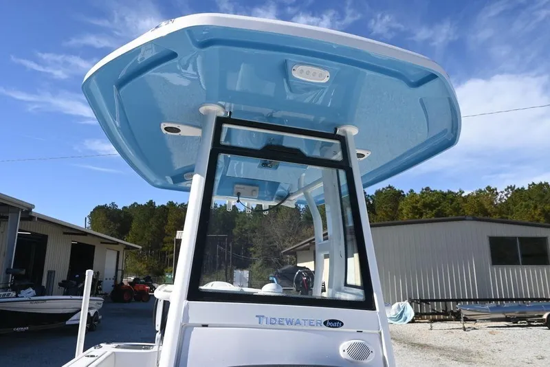 Slide: The Image of 2026 Tidewater 232 CC Adventure boat with blue T-top, parked outdoors. - 20