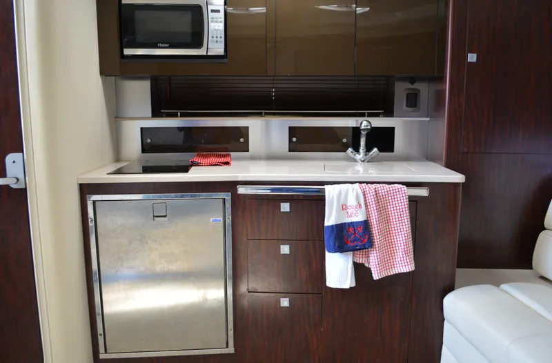Slide: The Image of 2013 Monterey 340 Sport Yacht kitchen with microwave, sink, and stainless steel fridge. - 19