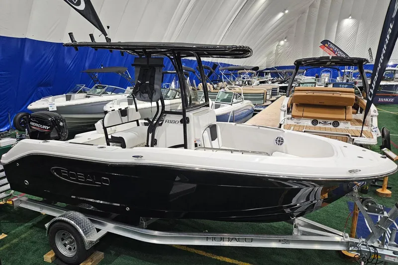 Slide: The Image of 2025 Robalo R180 Center Console boat on display in showroom with trailer. - 2