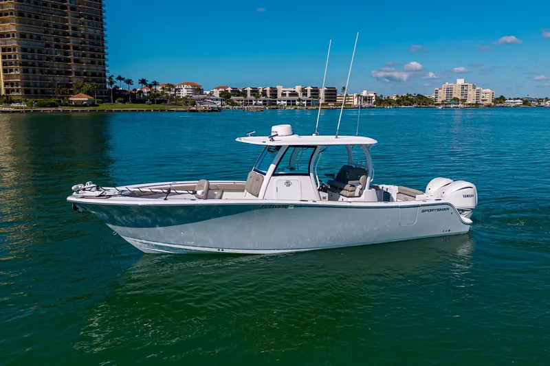 Slide: The Image of 2023 Sportsman Open 302 Center Console boat on calm water, cityscape background. - 2
