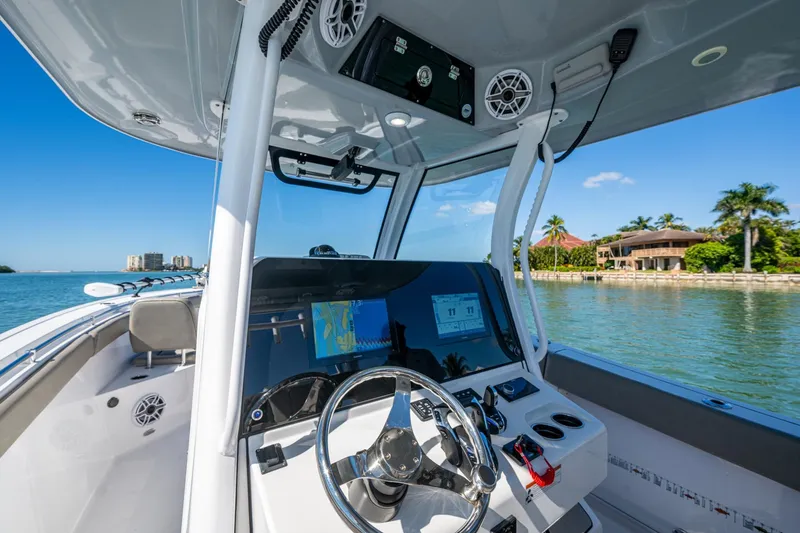 Slide: The Image of 2023 Sportsman Open 302 Center Console boat interior with navigation system, steering wheel, and waterfront view. - 34
