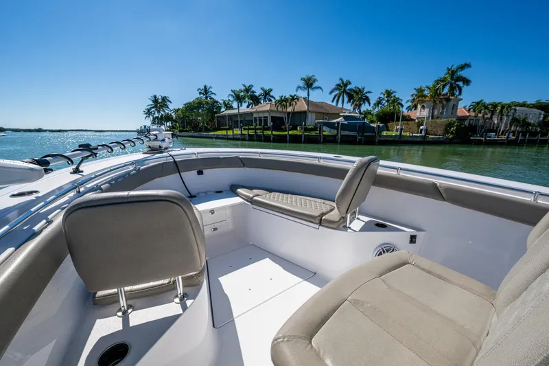 Slide: The Image of 2023 Sportsman Open 302 Center Console boat interior with seating, on a sunny waterfront. - 39