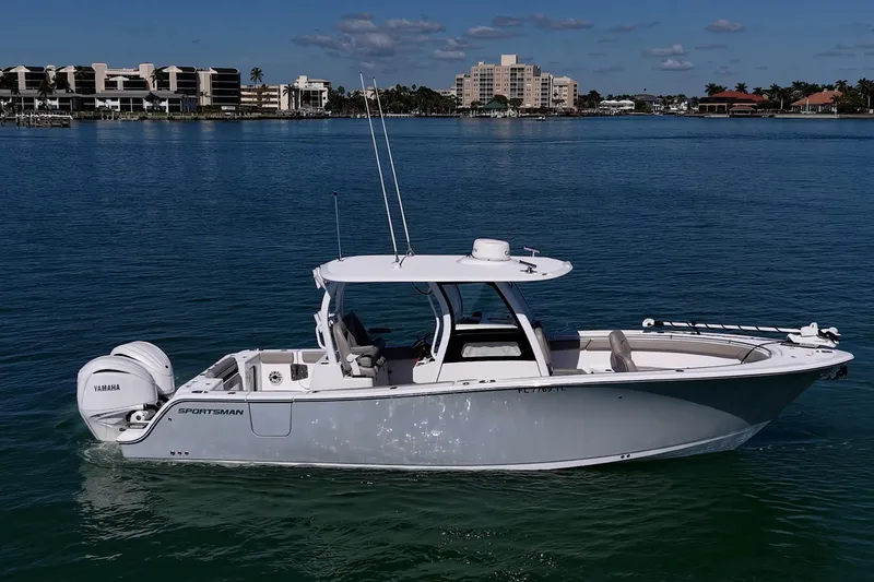 Slide: The Image of 2023 Sportsman Open 302 Center Console boat on calm water, cityscape background. - 48