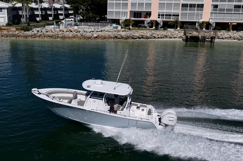 Slide: The Image of 2023 Sportsman Open 302 Center Console boat cruising near waterfront buildings. - 58