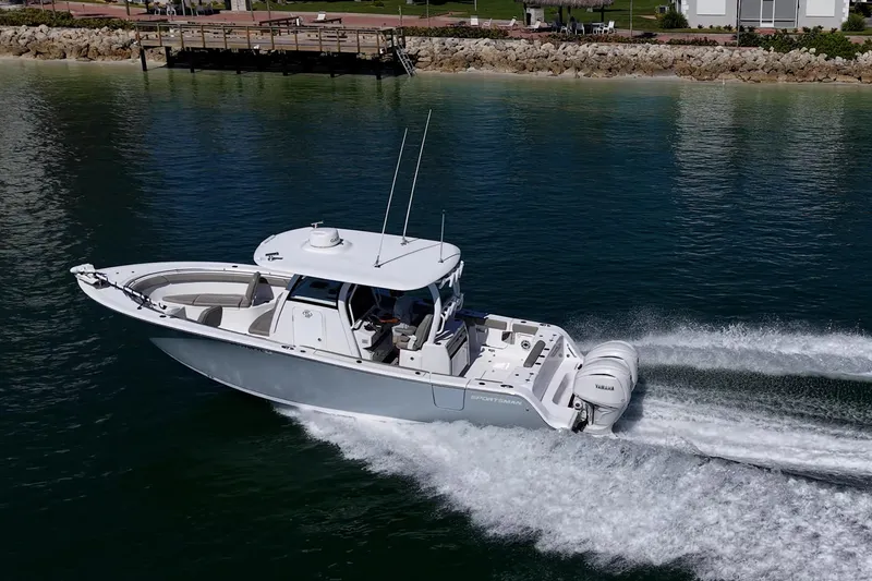 Slide: The Image of 2023 Sportsman Open 302 Center Console boat cruising on calm water near a dock. - 59
