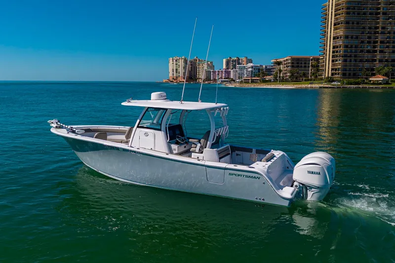Slide: The Image of 2023 Sportsman Open 302 Center Console boat cruising near coastal cityscape. - 7