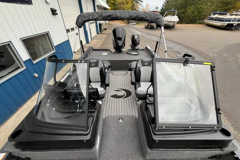 Slide: The Image of 2025 Crestliner 2050 Fish Hawk boat with open windshield and seating, docked near blue building. - 14