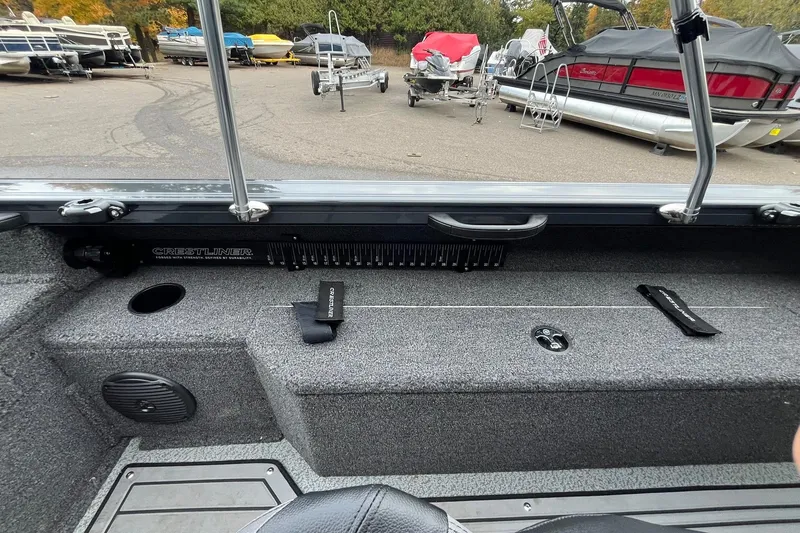 Slide: The Image of 2025 Crestliner 2050 Fish Hawk interior with storage and seating, in a boatyard setting. - 18
