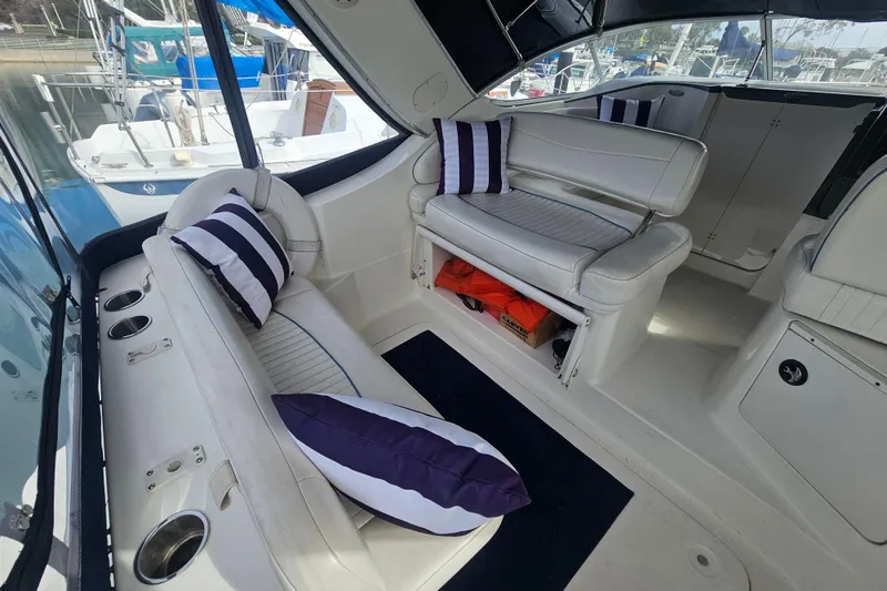 Slide: The Image of 2005 Bayliner 2855 Ciera interior with white seating and striped cushions in a marina setting. - 14