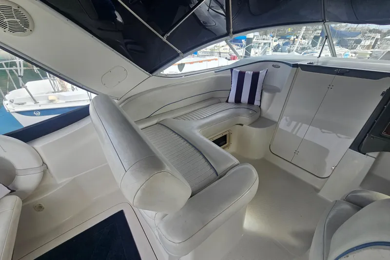 Slide: The Image of 2005 Bayliner 2855 Ciera interior with white seating and striped pillow, docked at marina. - 15