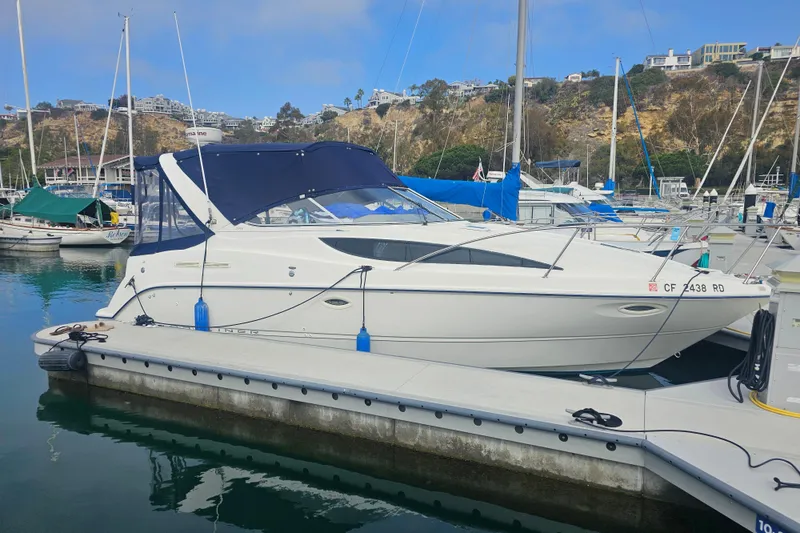 Slide: The Image of 2005 Bayliner 2855 Ciera docked at a marina with scenic hillside backdrop. - 2