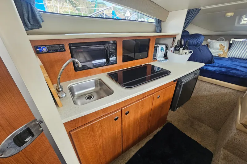Slide: The Image of 2005 Bayliner 2855 Ciera interior with kitchenette, sink, microwave, and cozy seating area. - 24