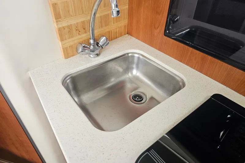 Slide: The Image of 2005 Bayliner 2855 Ciera kitchen sink with modern faucet and wooden accents. - 27