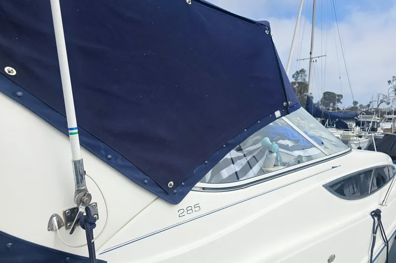 Slide: The Image of 2005 Bayliner 2855 Ciera boat with blue canvas cover in marina setting. - 3