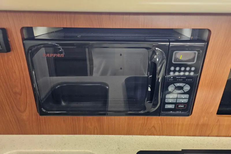 Slide: The Image of Microwave in 2005 Bayliner 2855 Ciera boat kitchen, featuring wood paneling. - 30
