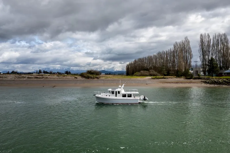 Slide: The Image of 2026 American Tug 362 cruising on a calm river under cloudy skies. - 4
