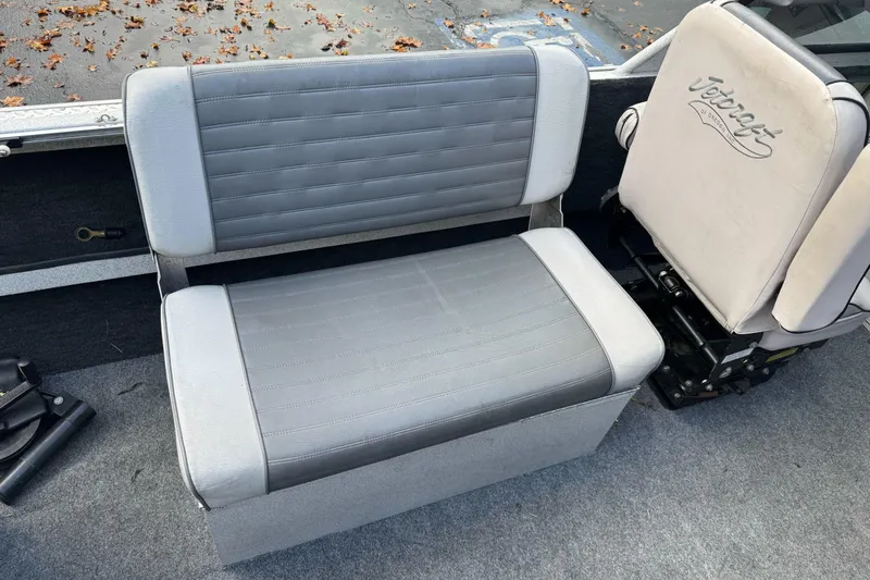 Slide: The Image of Gray seating in a 1994 Jetcraft Yukon boat, featuring a cushioned bench and branded chair. - 19