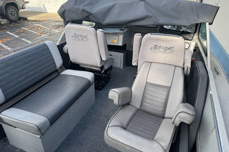 Slide: The Image of 1994 Jetcraft Yukon boat interior with gray seating and dashboard, parked outdoors. - 22