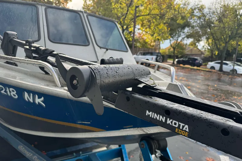 Slide: The Image of 1994 Jetcraft Yukon boat with Minn Kota Edge motor, parked outdoors on a rainy day. - 3