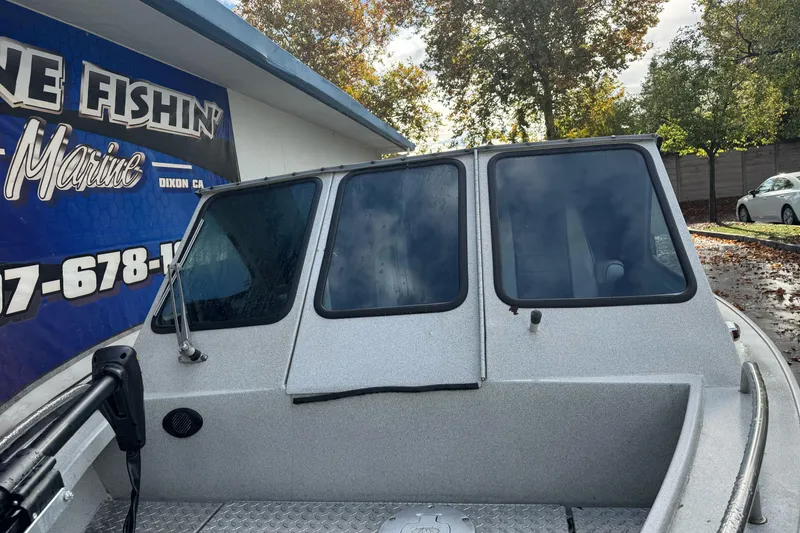 Slide: The Image of 1994 Jetcraft Yukon boat with windshield, parked near a marine shop. - 5