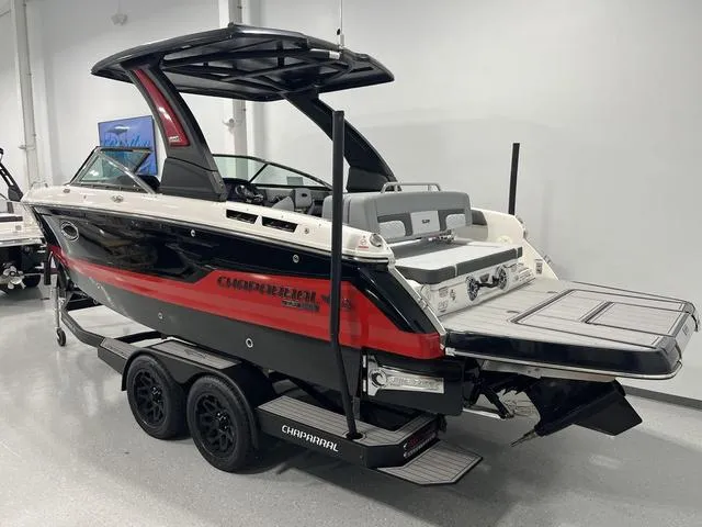 Slide: The Image of 2025 Chaparral 26 Surf boat on trailer, black and red design, in showroom setting. - 1