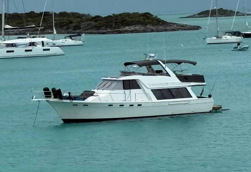 Slide: The Image of 1995 Bayliner 4788 Pilothouse Motoryacht anchored in turquoise waters, surrounded by other boats. - 1