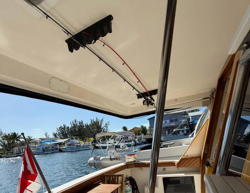 Slide: The Image of 1995 Bayliner 4788 Pilothouse Motoryacht interior with fishing rods, docked by waterfront homes. - 23