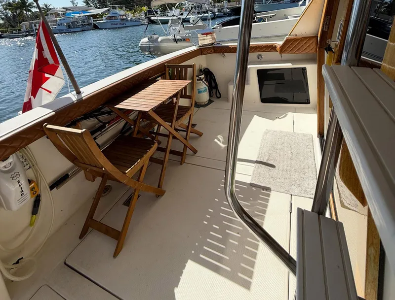 Slide: The Image of 1995 Bayliner 4788 Pilothouse Motoryacht deck with wooden chairs, table, and Canadian flag. - 24