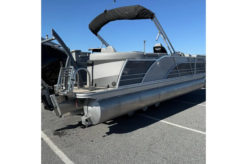 Slide: The Image of 2024 Berkshire 23E STS 3.0 pontoon boat with canopy, parked on asphalt under clear blue sky. - 9