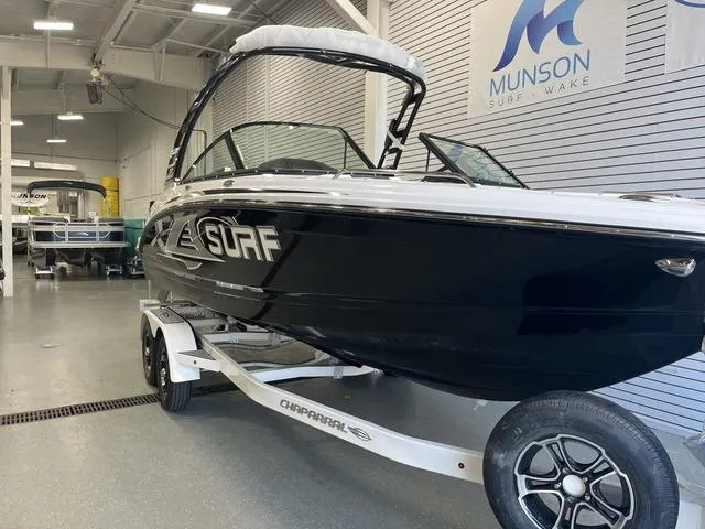 Slide: The Image of 2025 Chaparral 23 Surf boat in showroom, black exterior, on a trailer. - 2