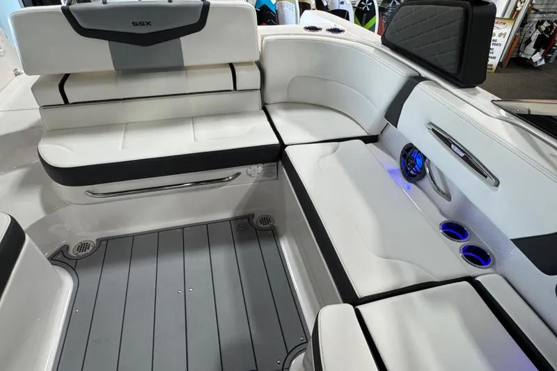 Slide: The Image of 2025 Chaparral 247 SSX boat interior with white seating, cup holders, and blue LED lighting. - 9